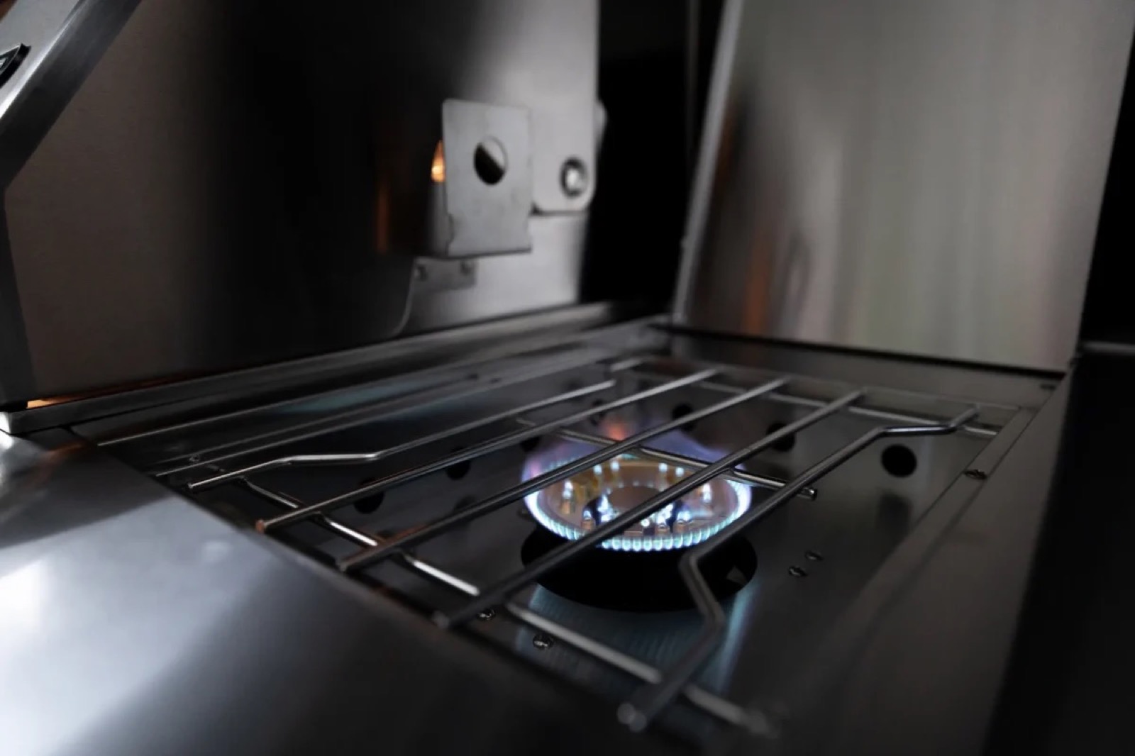 Geöffneter Grilldeckel mit Flamme