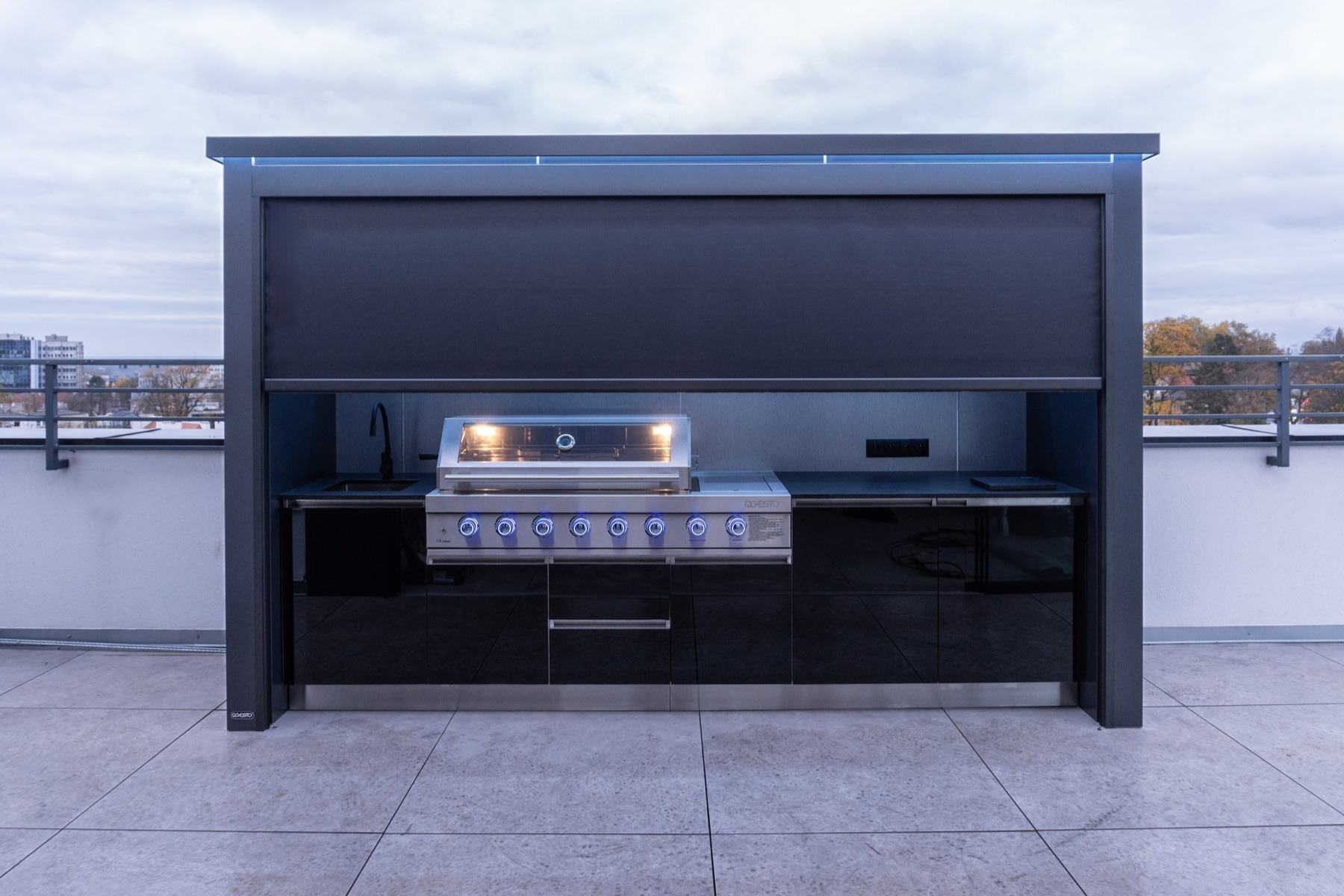 Geöffnete RULLA XXL Outdoor-Küche auf einer Dachterrasse mit beleuchtetem Grillbereich